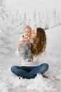Kiss mom. A mother sits in the artificial snow and kisses her baby son while holding him in her arms Royalty Free Stock Photo