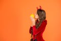 Kiss spell. Small girl kiss pumpkin orange background. Little child wear red devil horns for holiday celebration