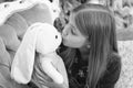 A kissable cutie. Small girl kiss rabbit toy. Little girl with cute bunny at Christmas tree. Little child play with soft