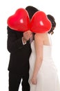 Kissing bridal pair with red heart ballons isolated over white.