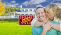 Kissing Couple In Front Sold Real Estate Sign and House Royalty Free Stock Photo