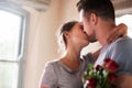 Kissing every moment we can. a young man surprising his girlfriend with a bunch of roses in their bedroom at home. Royalty Free Stock Photo
