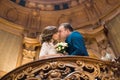 Kissing newlyweds while standing on the old baroque balcony with the wedding bouquet.