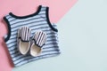 Kit of baby`s clothes on coloured background. Striped undershirt and tiny shoes for infant or toddler. Flat lay design.