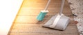 Kit of the grey plastic broom with green bristles for sweeping floors and dustpan put on the floor in house