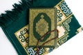 The Kitab of Al - Qur\'an is on the prayer rug and white background