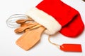 Kitchen accessories or kit of kitchenware packed in big red sock, white background. Christmas menu concept. Kitchenware