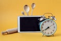 Kitchen accessories, tablet, alarm clock on a yellow background, side view-the concept of starting classes in cooking courses via