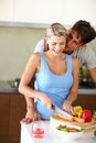 Kitchen affections. A young man standing behind his girlfriend as shes chopping vegetables at the kitchen counter. Royalty Free Stock Photo