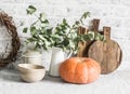 Kitchen autumn still life. Crockery, cutting boards, vine wreath, pumpkin on the table, on a light background. Rustic cozy style. Royalty Free Stock Photo