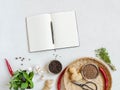 Kitchen background with open cookbook for recipes and various spices and herbs on light background. Top view. Copy space Royalty Free Stock Photo