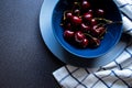 Kitchen background. Sweet dark cherries in a ceramic bowl on a dark background and kitchen towel with a blue lines Royalty Free Stock Photo