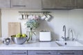 Kitchen in beige tones. Toaster. Mugs and milk jugs hang on hooks. Steel bowl with green apples. Bouquet of multi-colored Royalty Free Stock Photo