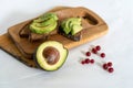 On the kitchen board half an avocado and slices on bread, avocado sandwich Royalty Free Stock Photo