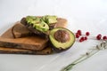 On the kitchen board half an avocado and slices on bread, avocado sandwich Royalty Free Stock Photo