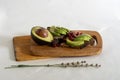 On the kitchen board half an avocado and slices on bread, avocado sandwich Royalty Free Stock Photo