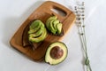 On the kitchen board half an avocado and slices on bread, avocado sandwich Royalty Free Stock Photo