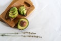 On the kitchen board half an avocado and slices on bread, avocado sandwich Royalty Free Stock Photo