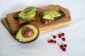 On the kitchen board half an avocado and slices on bread, avocado sandwich Royalty Free Stock Photo