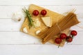 kitchen board with ingredients for an Italian meal seen from above with wholemeal spaghetti, tomato, parmesan, garlic and