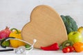 Kitchen board in the shape of heart, vegetables, fruits and stethoscope. Healthy diet food concept Royalty Free Stock Photo