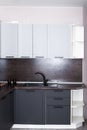 Kitchen with brown countertop and black sink, light gray cabinet drawers. Kitchen interier