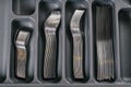 Kitchen cabinet open drawer with black cutlery organizer tray with forks, spoons, knives. Storage organization system