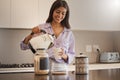 Kitchen, coffee and morning with a woman pouring a drink or fresh beverage in her home for caffeine. Kettle, water and Royalty Free Stock Photo
