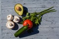 A kitchen composition of an appetizing half of an avocado, tomato, cucumber, raw champignons and parsley