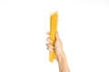 The kitchen and the cooking theme: man's hand holding a stack of raw spaghetti on an isolated white background in studio