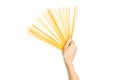 The kitchen and the cooking theme: man's hand holding a stack of raw spaghetti on an isolated white background in studio