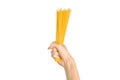 The kitchen and the cooking theme: man's hand holding a stack of raw spaghetti on an isolated white background in studio