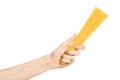 Kitchen and Cooking topic: human hand holding a pile of dry yellow spaghetti isolated on white background in studio