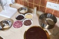 Kitchen counter with baked biscuit, chips of various organic chocolate in bowls, bordure baking film and food processor