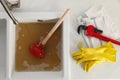 Kitchen counter with clogged sink, plunger and plumber`s accessories, flat lay Royalty Free Stock Photo