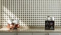 Kitchen counter with coffee mugs and copper hammered cups on it with ceramic small diamond tiles wall, under morning sunshine, 3d