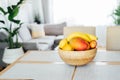 Kitchen counter table with focus on bamboo bowl with exotic fruits on it with blurred background of modern cozy living