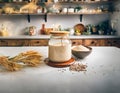 A kitchen countertop featuring a jar of sourdough starter and various seeds on a white table. Healthy fermentation process.