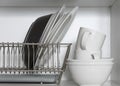 Kitchen cupboard with a lattice for dishes, with a white and black plate, cups, and a drip tray