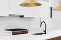 A white kitchen detail with gold light fixtures, marble countertop and black faucet. Royalty Free Stock Photo