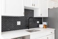 A kitchen detail with white cabinets and black subway tile backsplash. Royalty Free Stock Photo