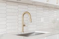 A kitchen detail with white cabinets, gold faucet, and tiled backsplash. Royalty Free Stock Photo