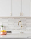 A kitchen detail with white cabinets, gold faucet, and tiled backsplash. Royalty Free Stock Photo