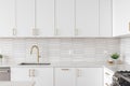 A kitchen detail with white cabinets, gold faucet, and tiled backsplash. Royalty Free Stock Photo