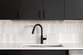 A kitchen faucet detail with black cabinets and subway tile backsplash. Royalty Free Stock Photo