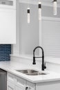 A kitchen faucet detail with a black faucet, modern light fixtures, and blue backsplash. Royalty Free Stock Photo