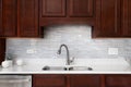 A kitchen faucet detail with dark wood cabinets and a glass tile backsplash. Royalty Free Stock Photo
