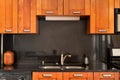 A kitchen faucet detail with wood cabinets and black countertop.