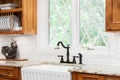 A kitchen faucet detail with wood cabinets and a white farmhouse sink. Royalty Free Stock Photo