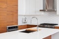 A kitchen faucet detail with wood and white cabinets and a hexagon backsplash. Royalty Free Stock Photo